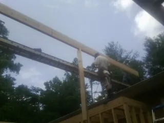 Carpenter setting a ridge beam over a new addition frame — Ice Dam Removal by Roofing Brothers in Corona