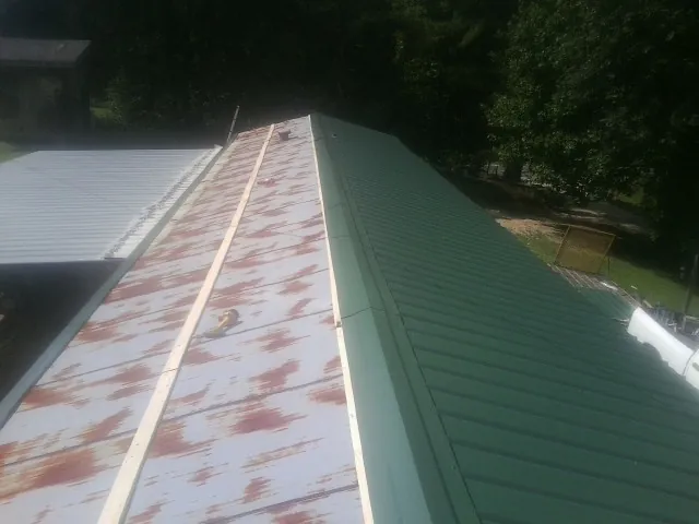 Old rusted panels beside newly installed green metal roofing — Wind Damage Roof Repair by Roofing Brothers in Corona