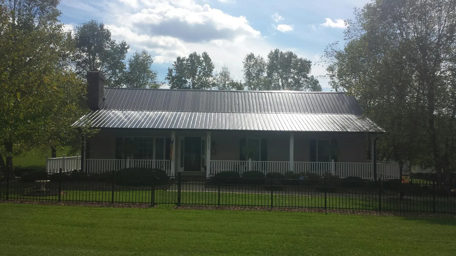Gray metal roof on a brick ranch with a full width front porch — Gutter Guard Installation work by our crew in Corona
